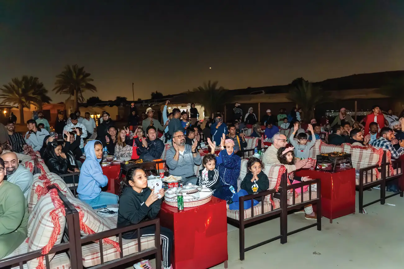 Guests seated for dinner at an outdoor desert camp at night