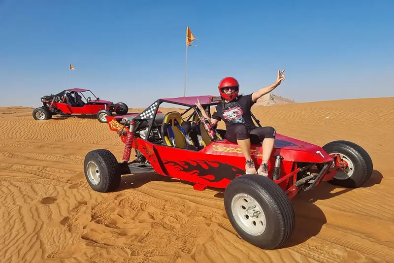 Guest beside a red custom buggy in the desert