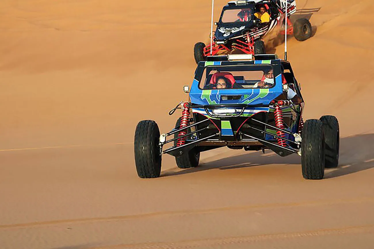 Custom buggies driving in a line across the dunes